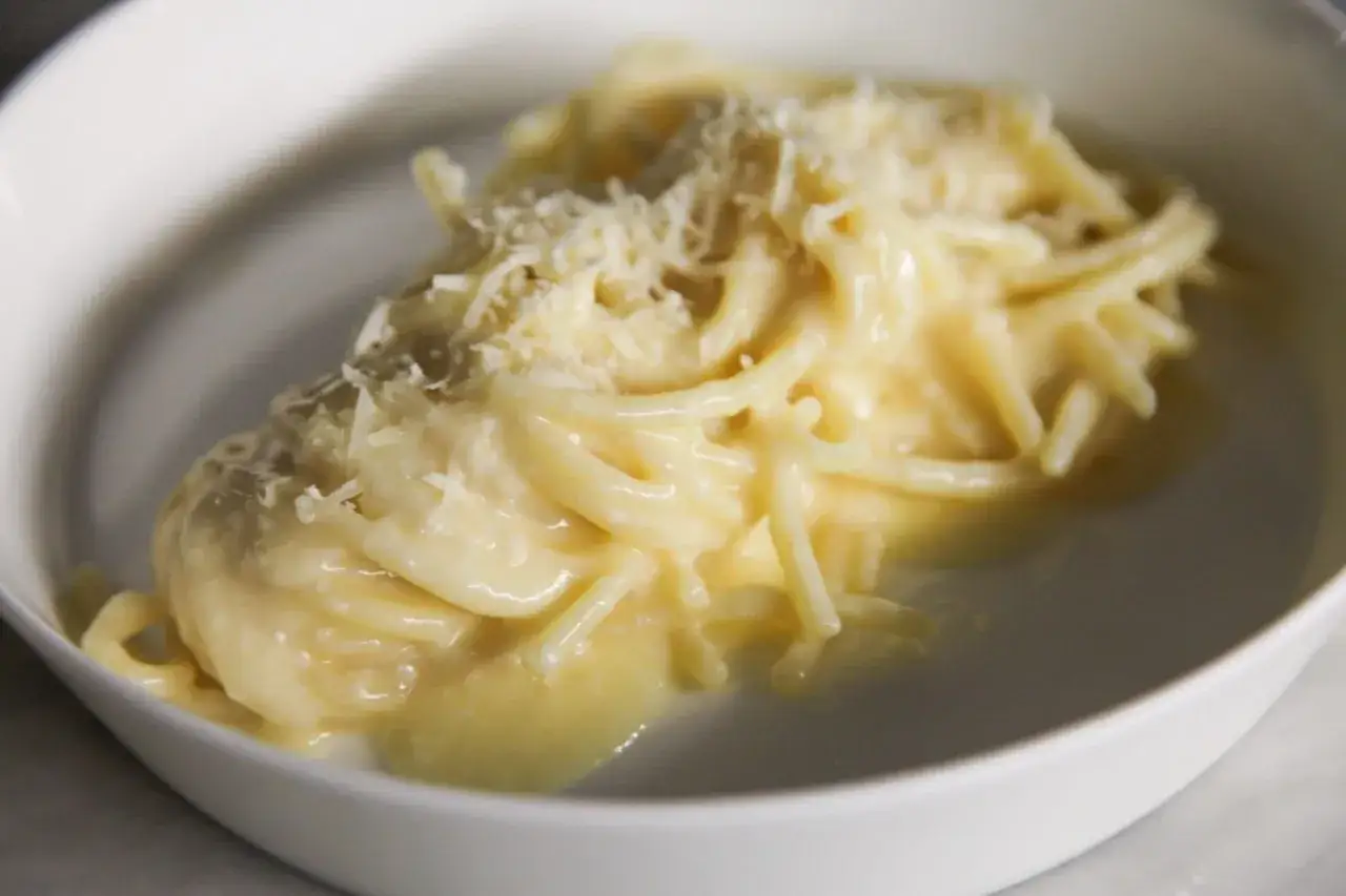 Un piatto di pasta in bianco cremosa, condita con abbondante parmigiano grattugiato.
