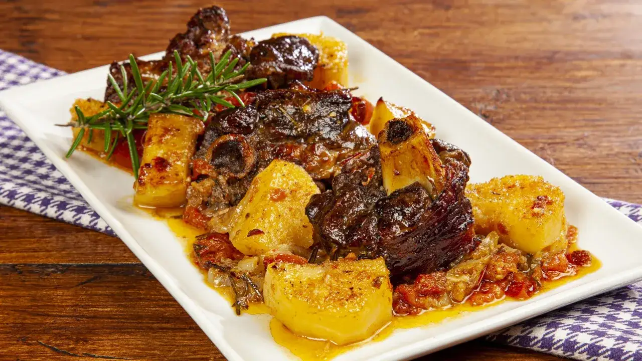 Succulento abbacchio al forno con patate dorate e rosmarino, un piatto che profuma di tradizione e sapori autentici.