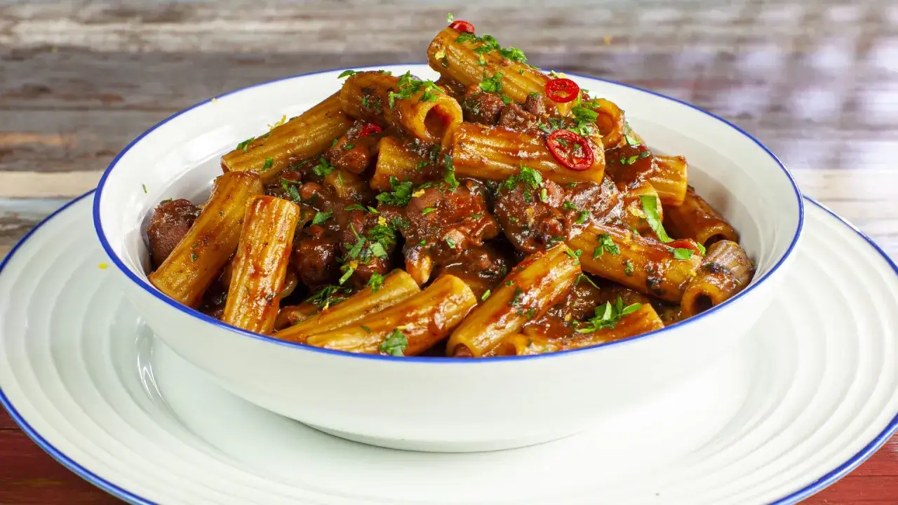 Rigatoni conditi con un ricco ragù di polpo, guarniti con prezzemolo fresco e peperoncino.