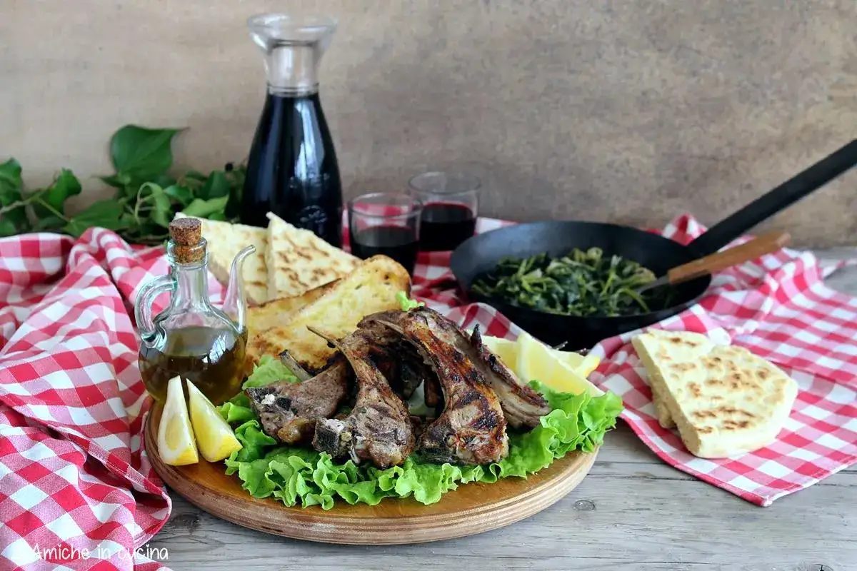Succulente costolette di agnello grigliate, servite con pane pita, verdure saltate, limone, olio d'oliva e vino rosso.