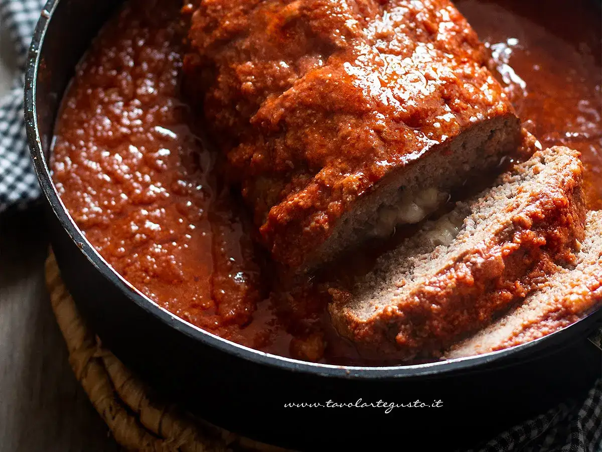 Polpettone al forno morbido, succulento e ripieno di formaggio filante, immerso in una ricca salsa al pomodoro.