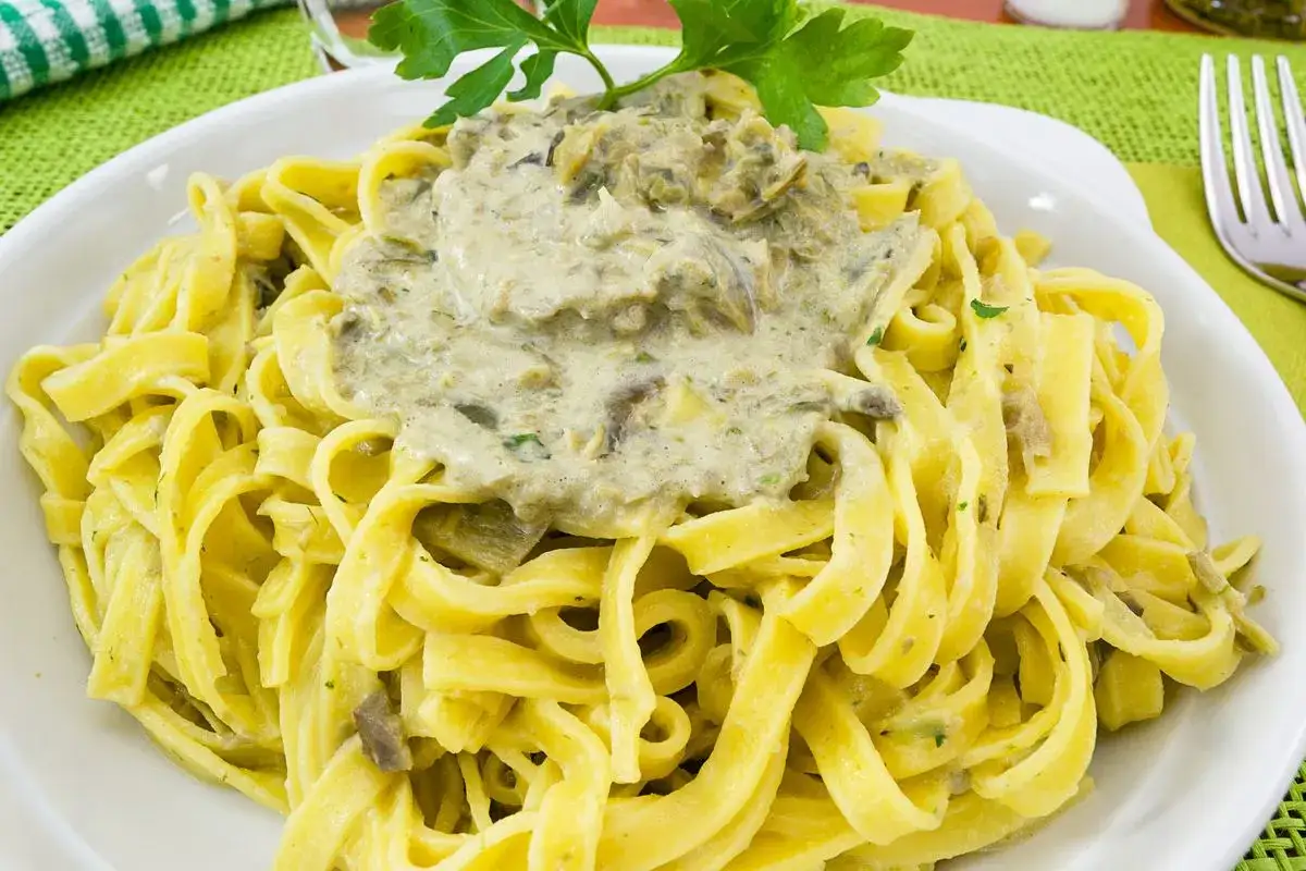 Pasta fresca con un cremoso sugo di carciofi alla siciliana, guarnita con prezzemolo fresco.