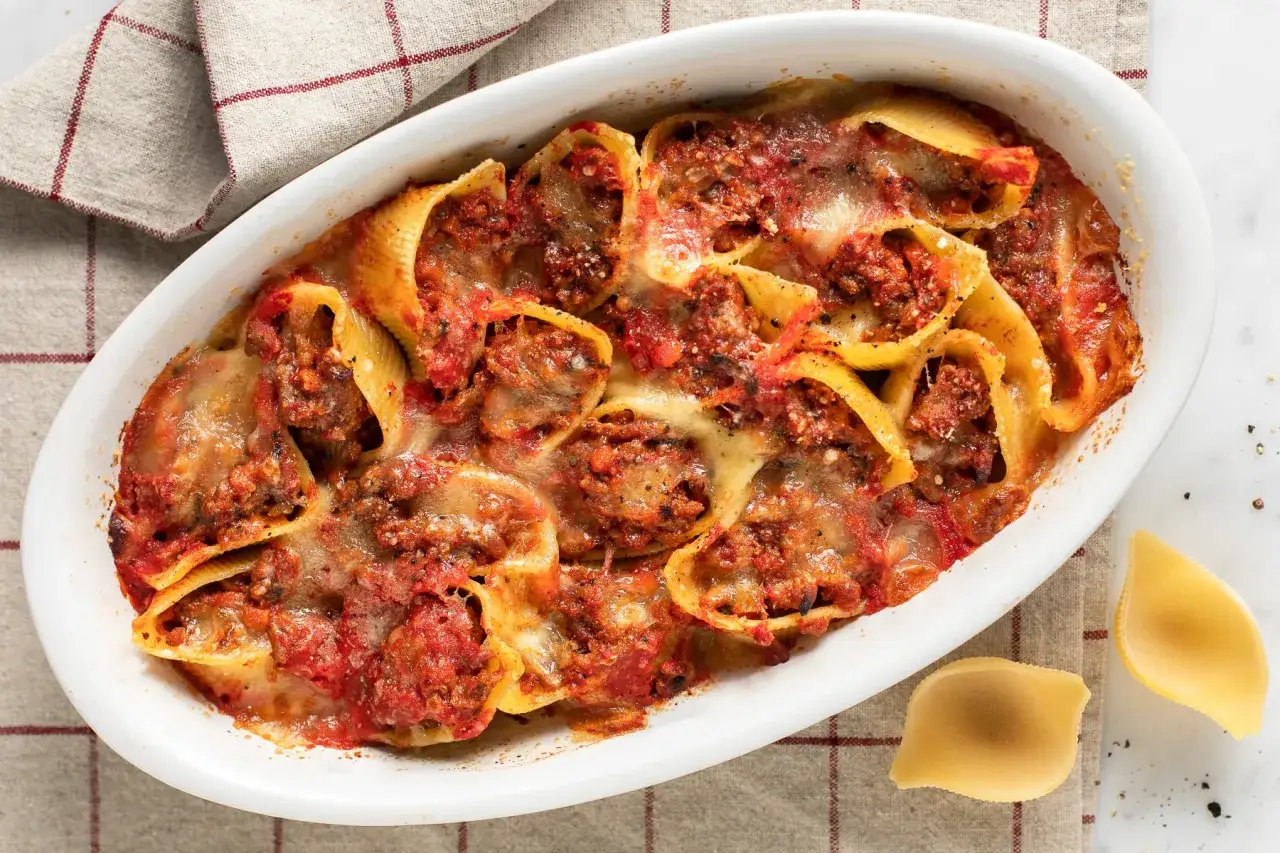 Conchiglioni ripieni al forno, ricoperti di sugo e formaggio fuso, pronti per essere gustati.