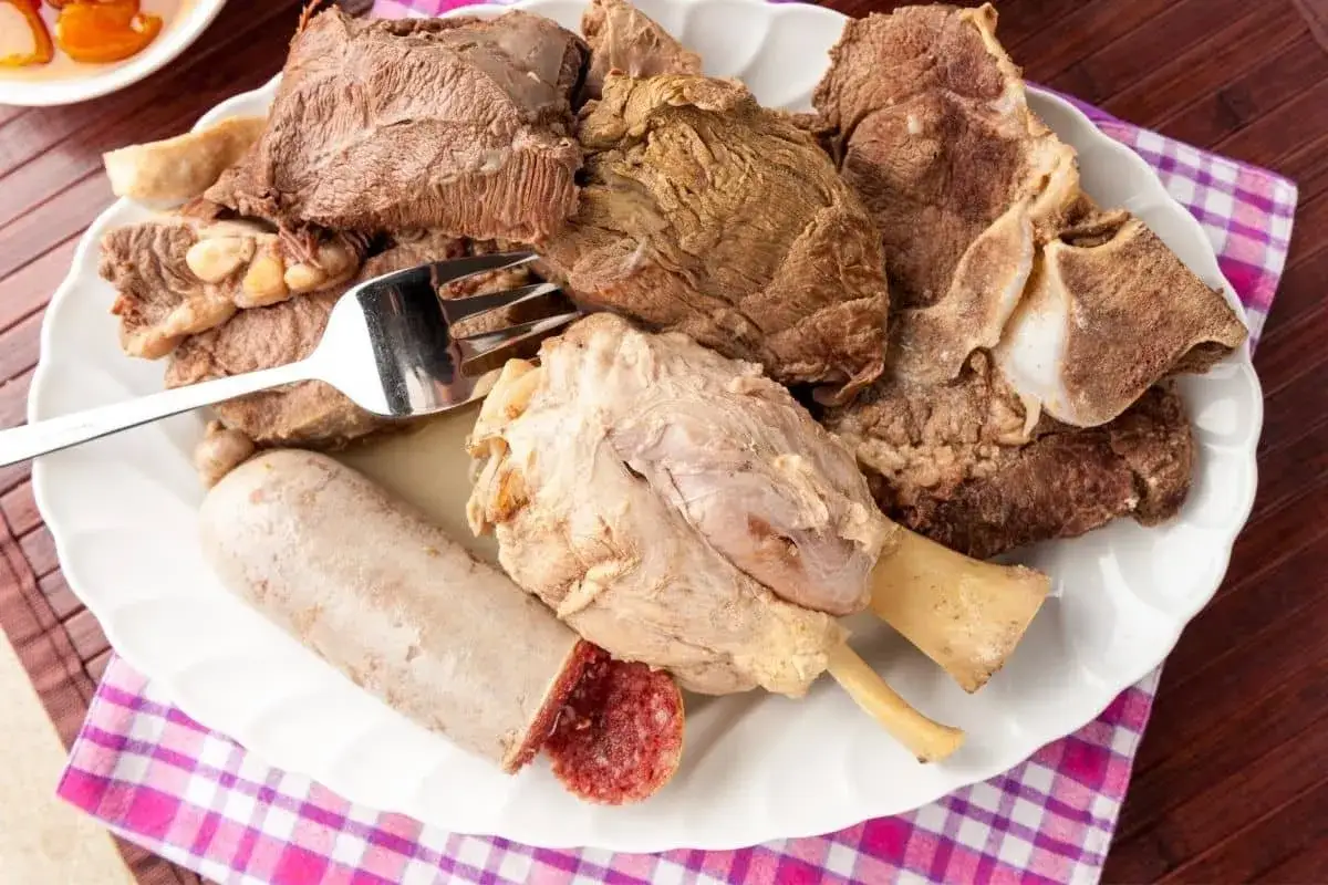 Piatto di bollito di carne misto, con pezzi di manzo, ossobuco e insaccato, pronto per essere gustato.