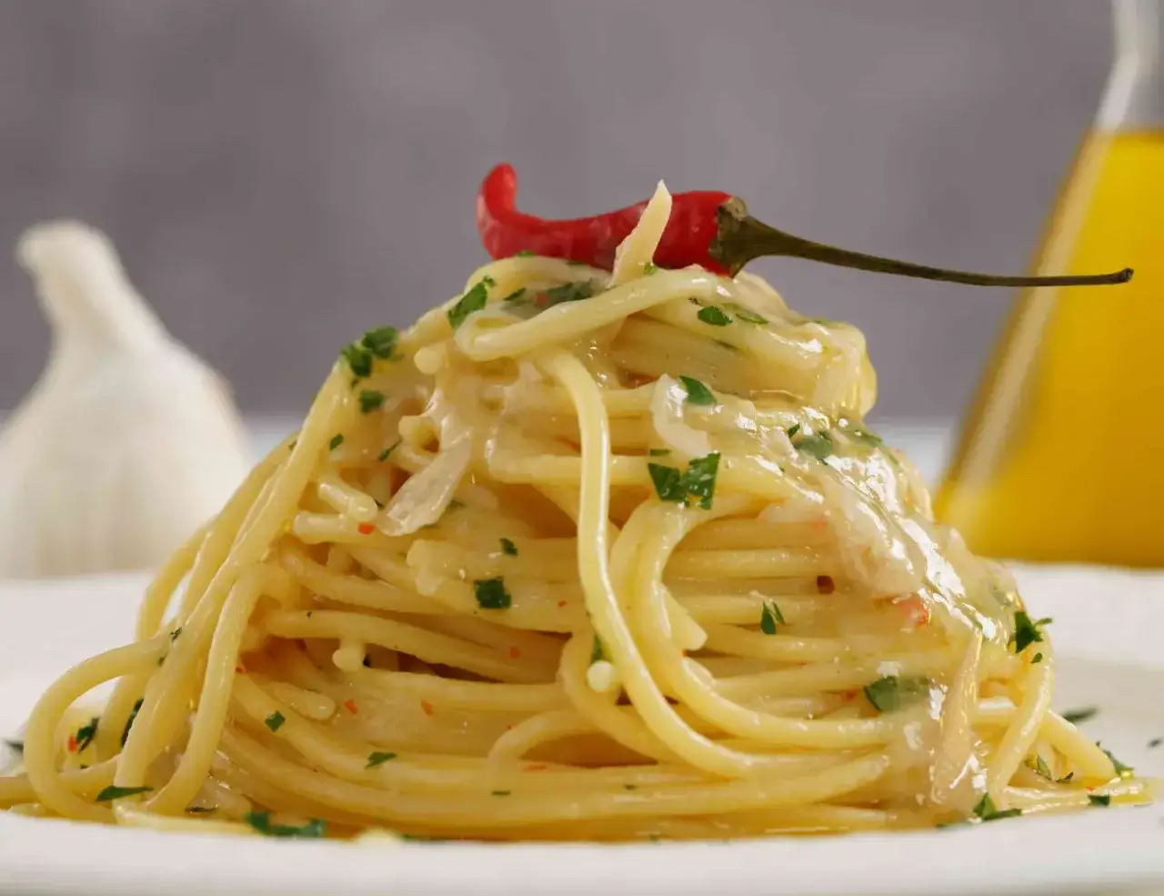 Un invitante piatto di pasta alla carrettiera, condita con aglio, olio e peperoncino, guarnita con un peperoncino rosso e prezzemolo.