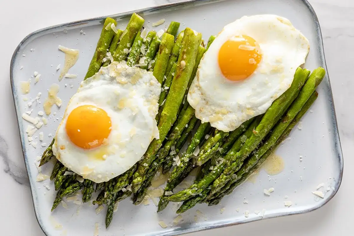 Asparagi cotti al forno con uova all'occhio di bue e scaglie di parmigiano. Un modo semplice e gustoso per scoprire come cucinare gli asparagi.