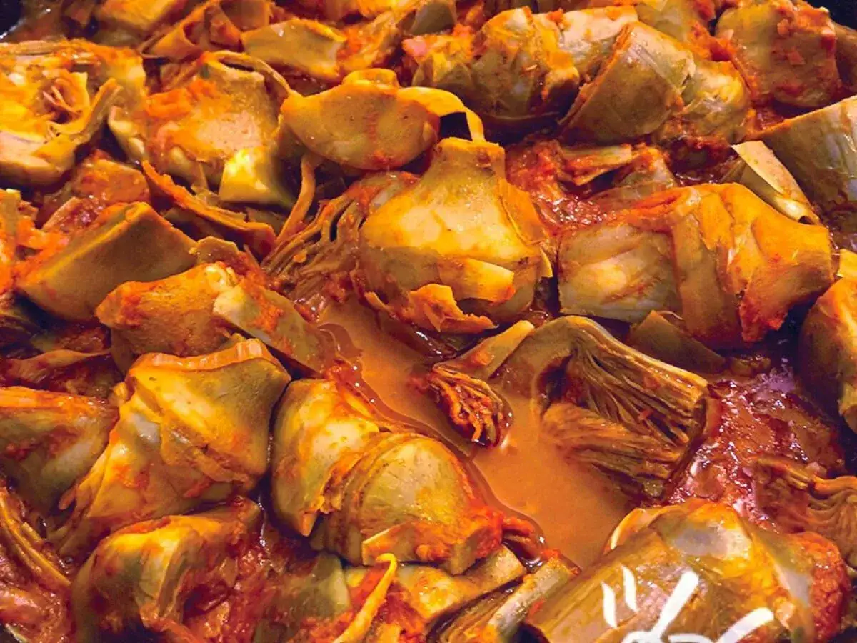 Un primo piatto succulento: carciofi in umido, cotti lentamente in un sugo rosso e profumato, pronti per essere gustati.