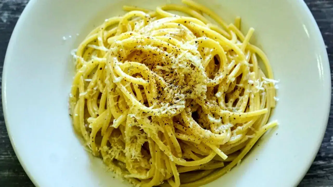 Un piatto di spaghetti fumanti, conditi con abbondante pecorino e pepe nero macinato fresco, un classico cacio e pepe.