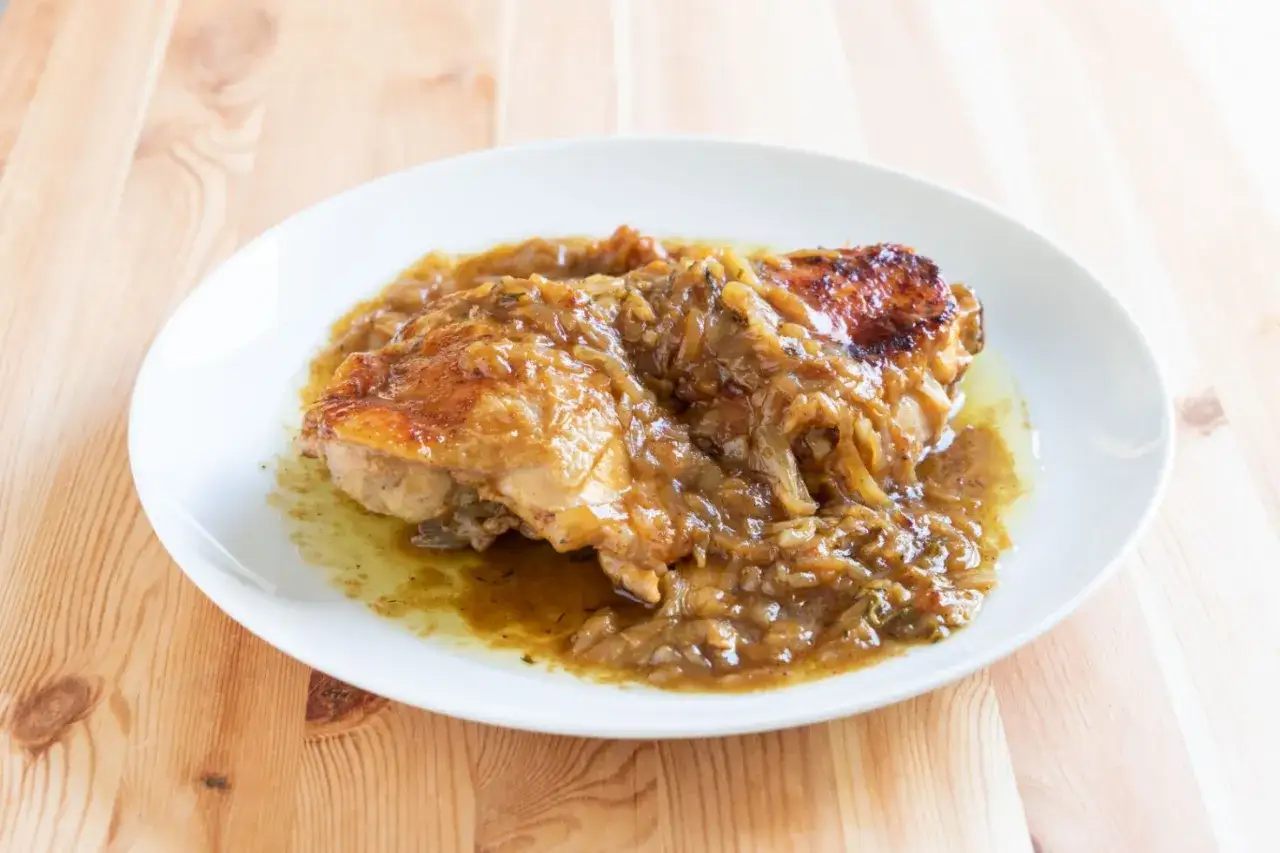 Pollo alla birra succulento, cotto lentamente con cipolle caramellate e una salsa dorata.