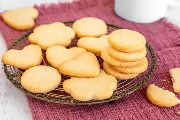Biscotti classici a forma di cuore e fiore, impilati su una gratella dorata, pronti per essere gustati.