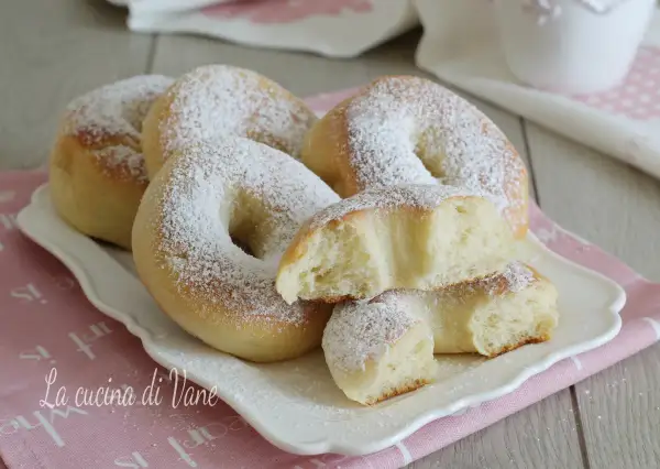 Ciambelle al forno soffici e profumate, cosparse di zucchero a velo, pronte per una colazione golosa.