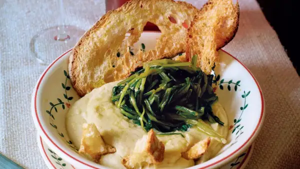 Piatto di fave e cicoria con crostini di pane abbrustolito. Un classico della cucina italiana, gustoso e salutare.
