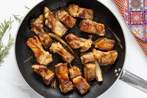 Costine di maiale in padella, dorate e succulente, profumate al rosmarino. Un piatto invitante pronto per essere gustato.