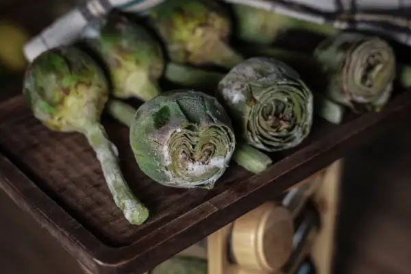 Carciofi freschi su un tagliere di legno, pronti per imparare come congelare i carciofi e conservarli per l'inverno.
