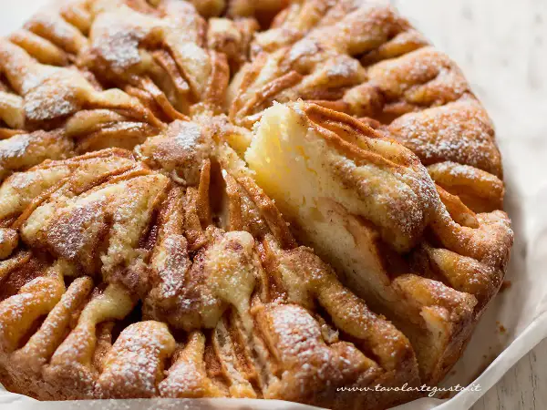 Una torta di mele umida e soffice, con un impasto dorato e mele caramellate, spolverata di zucchero a velo.
