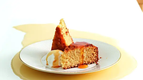 Fetta di torta al cocco con gelato alla vaniglia e sciroppo dorato.