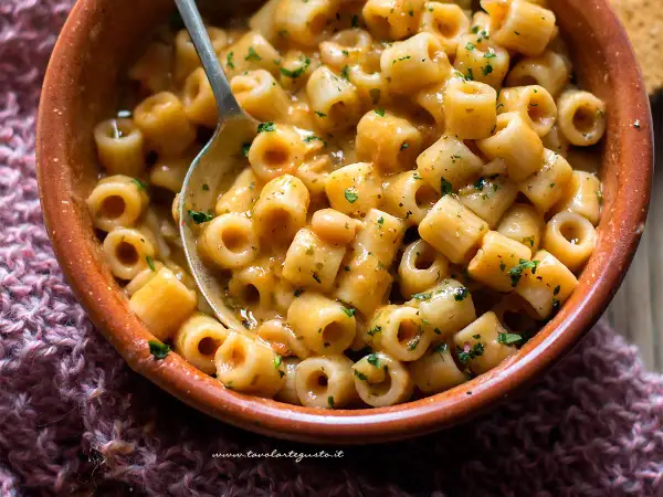 Un piatto fumante di pasta e fagioli, la ricetta della nonna, con ditalini e fagioli in un sugo cremoso, guarnito con prezzemolo tritato.