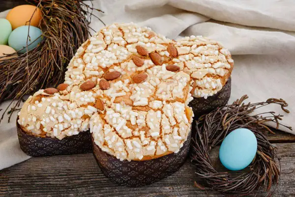 Colomba pasquale con glassa croccante, mandorle e zuccherini, decorata con uova e nidi di Pasqua.