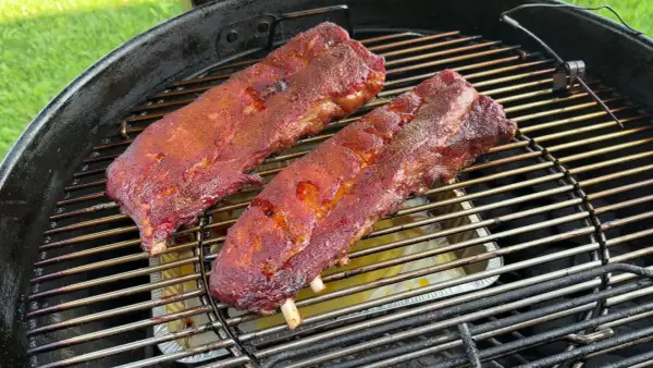 Costine al forno succulente e speziate che cuociono lentamente su una griglia, pronte per essere gustate.