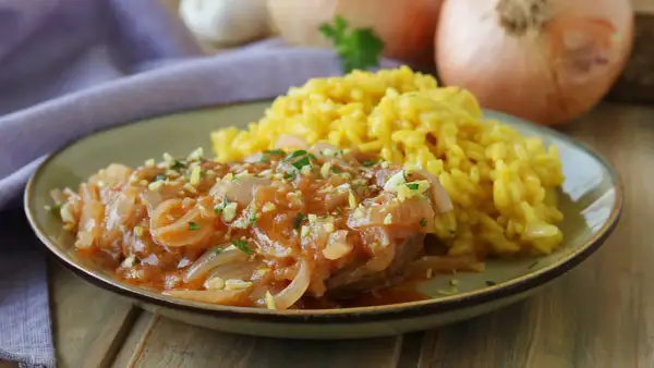 Un succulento ossobuco alla milanese, tenero e saporito, servito con un cremoso risotto giallo.