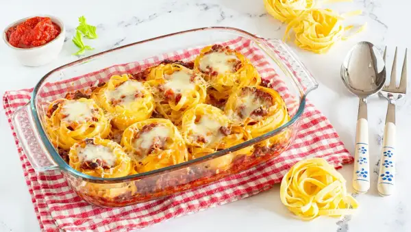 Nidi di tagliatelle al forno con ragù e formaggio fuso, pronti per essere gustati.