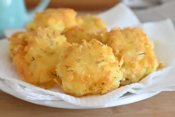 Frittelle di patate dorate e croccanti, condite con erbe aromatiche, servite su carta assorbente.
